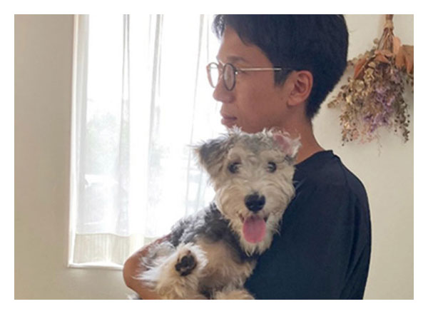 愛犬のミニチュアシュナウザーを抱きかかえるT.I.さん